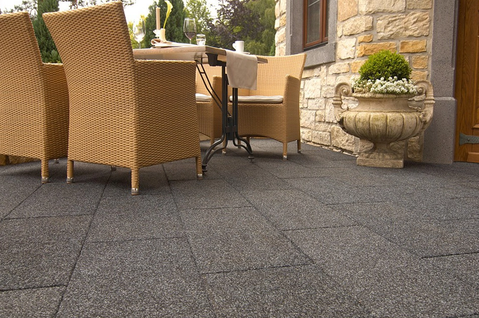 Elegante Terrasse mit grauem Gummibelag und Rattanmöbeln