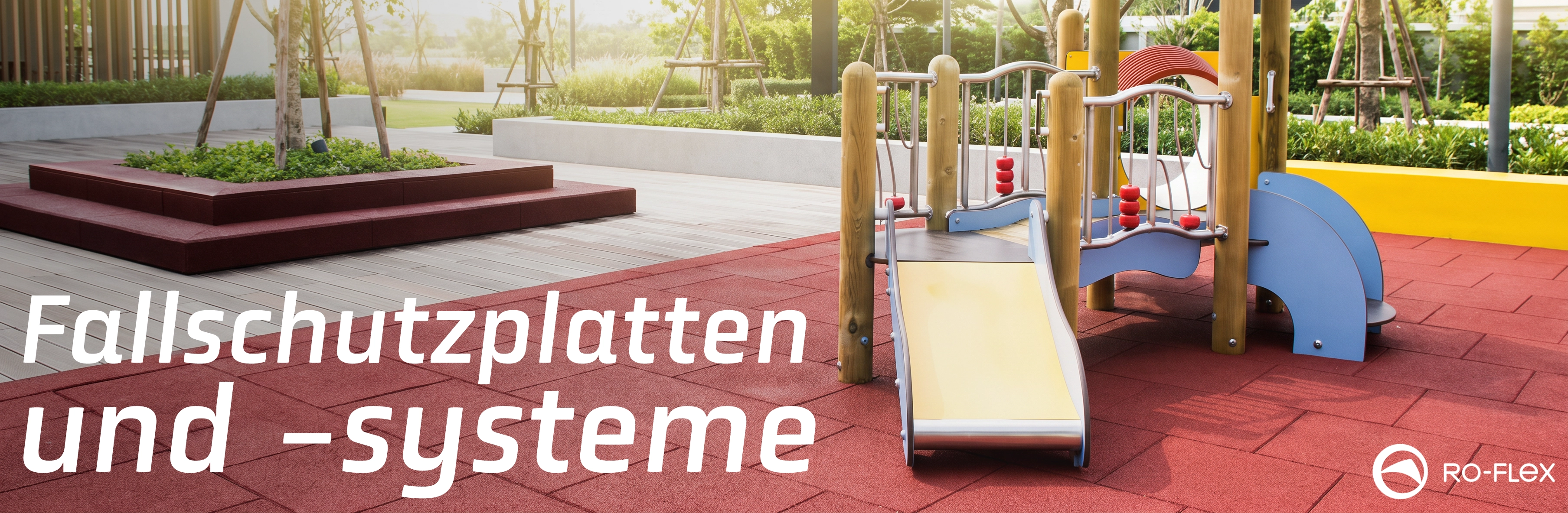 Zeitgemäßer Außen-Spielplatz mit Holzrutsche und bunten Elementen auf roten Gummi-Sicherheitsplatten, umgeben von modernem Holzboden und grünen Beeten bei sonnigem Licht